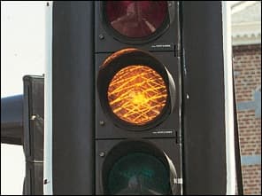 Photo d'un feu de circulation dont le feu orange est allumé, avec les feux rouge et vert éteints.