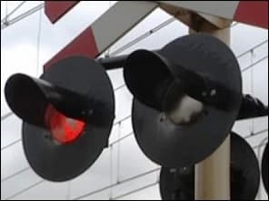 Photo rapprochée de deux feux rouges de passage à niveau, dont un est allumé.